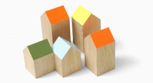 Houten blokjes in de vorm van een huisje met gekleurde schuine daken in een groepje bij elkaar