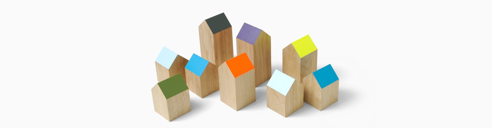 Houten blokjes in de vorm van een huisje met gekleurde schuine daken